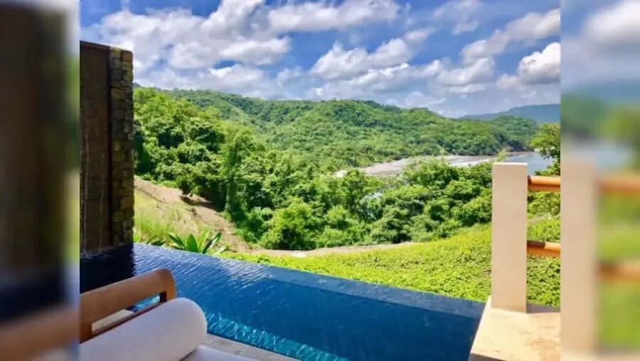 Infinity Pool und grüner Hügelblick unter blauem Himmel