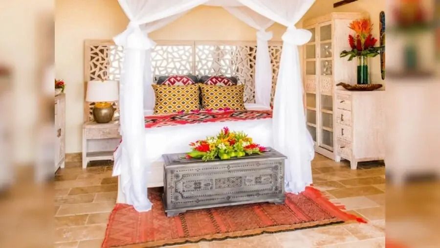 Elegantes Schlafzimmer mit Baldachinbett und dekorativen Kissen in warmer Atmosphäre