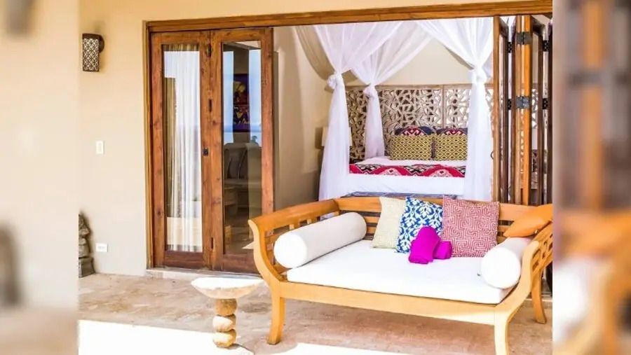 Offenes Schlafzimmer mit Zugang zur Terrasse und stilvollen Holzmöbeln