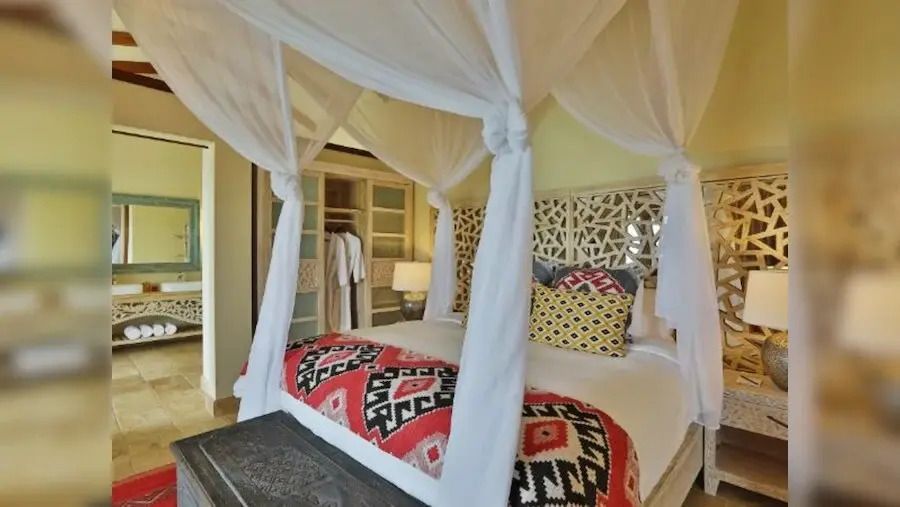 Gemütliches Schlafzimmer mit Baldachinbett und bunten Kissen in Villa.
