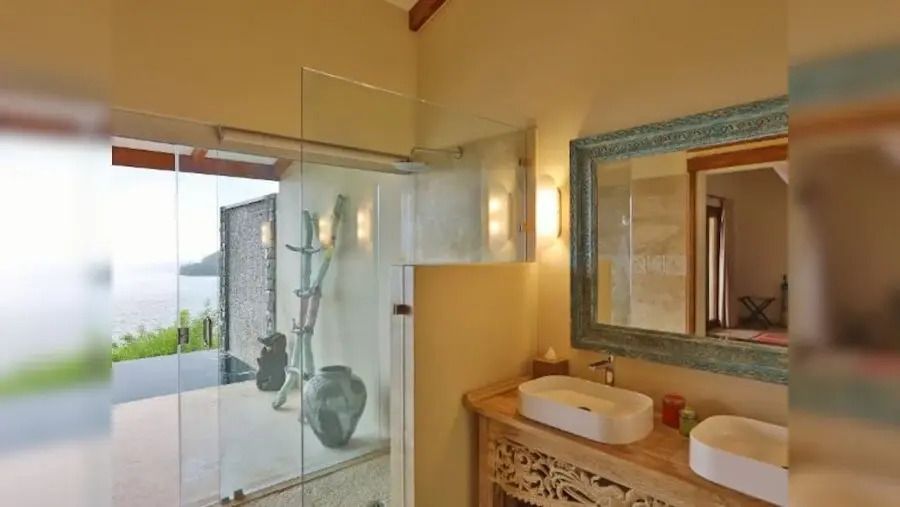 Modernes Badezimmer mit Glasdusche und kunstvollem Waschbecken.