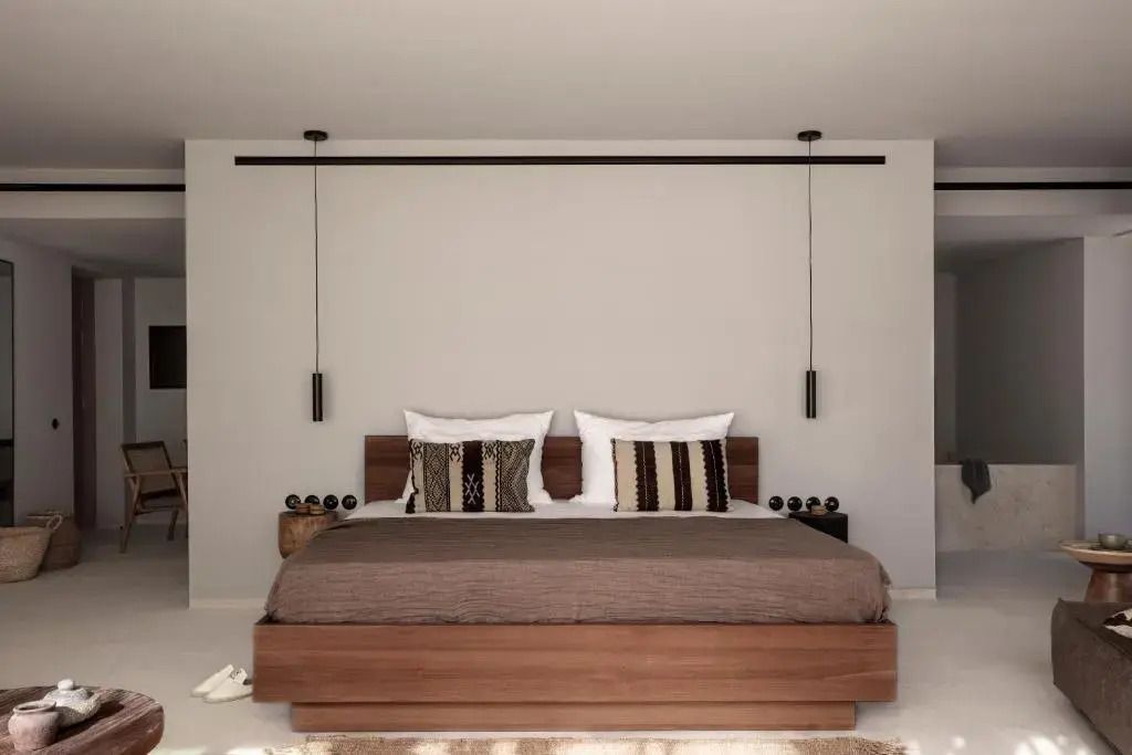 Modernes Doppelbett mit dekorativen Kissen und hängenden Lampen in der Suite