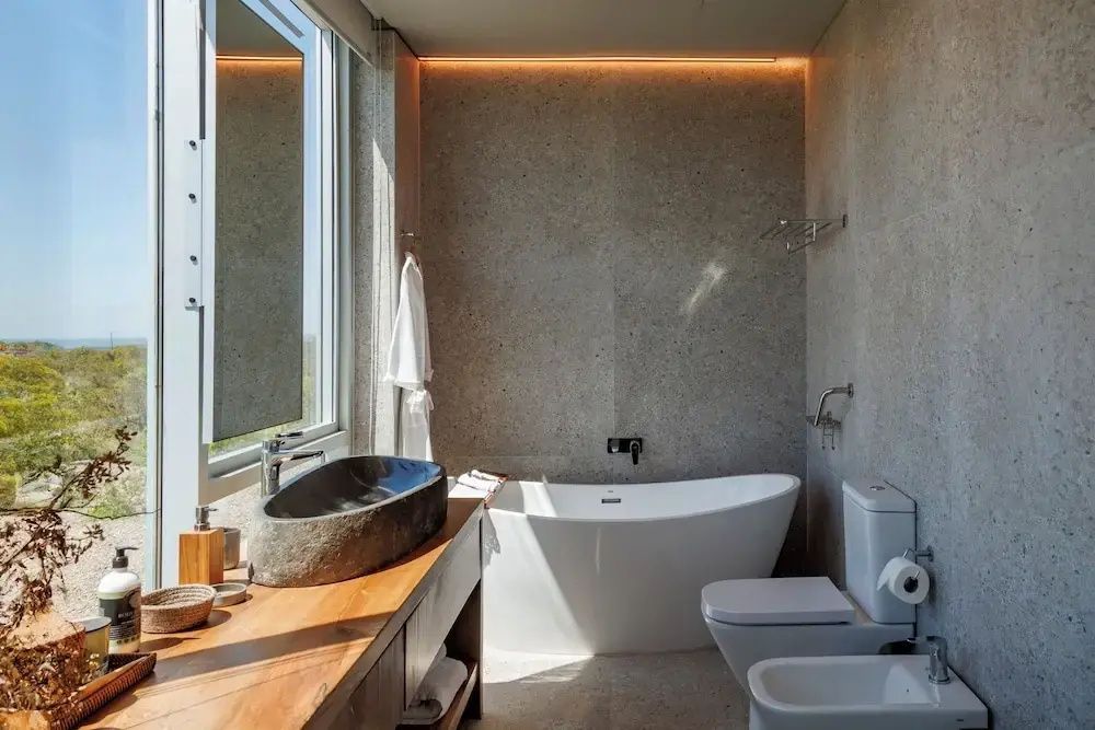 Modernes Badezimmer mit freistehender Badewanne und Natursteinwaschbecken