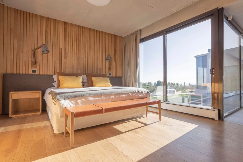 Holzverkleidetes Zimmer mit hellem Doppelbett und großen Fenstern