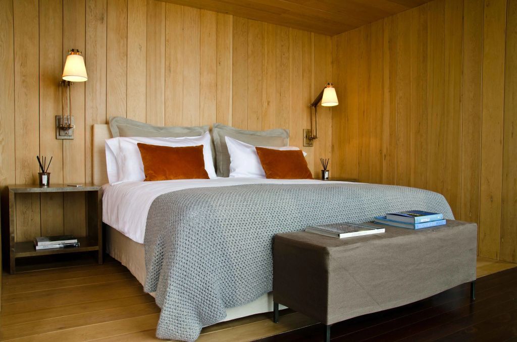 Gemütliches Schlafzimmer mit Holzwänden und luxuriösen Kissen.
