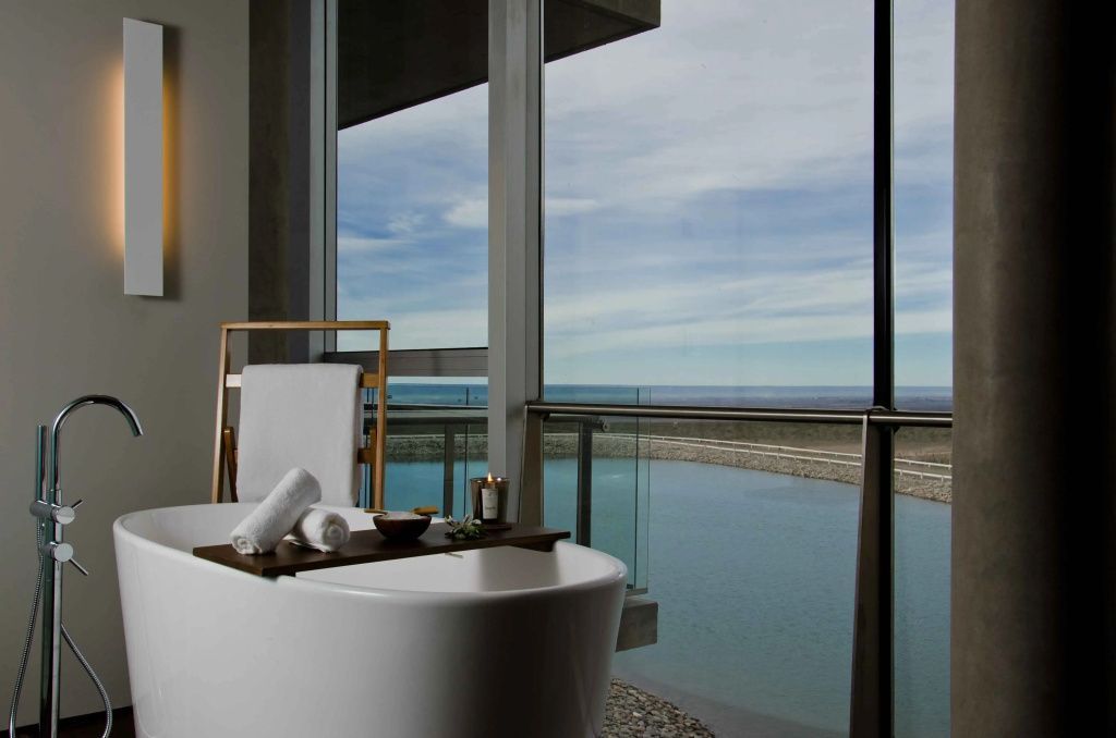 Moderne Badewanne mit Aussicht auf Wasser und Weinberge.