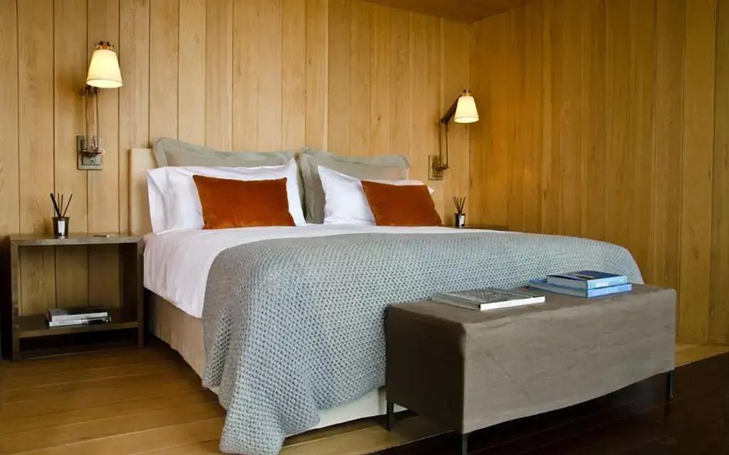 Gemütliches Bett in der Superior Suite mit Holzwänden und eleganten Kissen