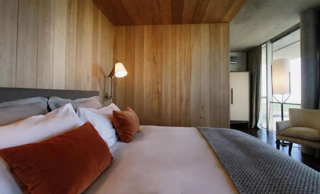 Bett mit stilvoller Beleuchtung in der Superior Suite mit Holzverkleidung