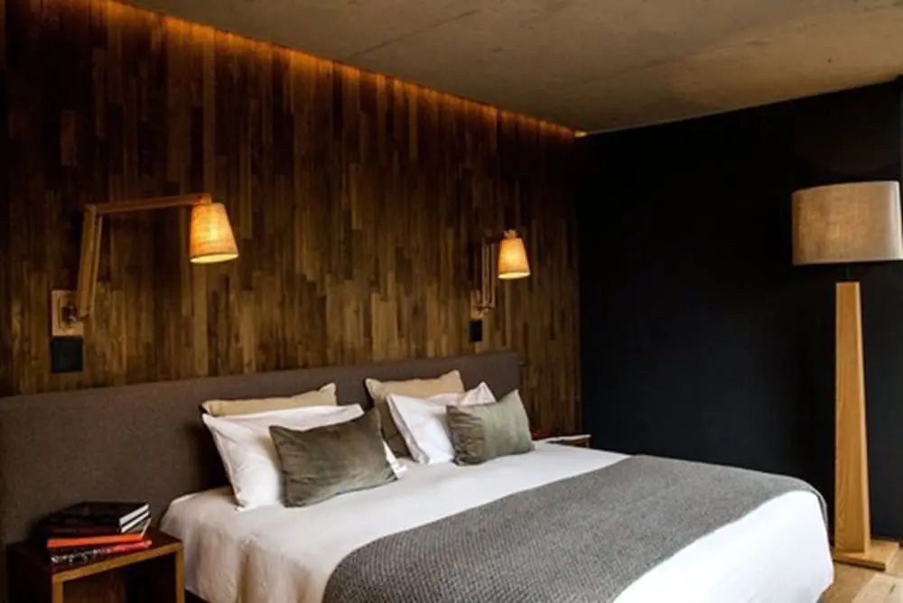 Stilvoll eingerichtetes Schlafzimmer mit Holzwand und modernen Lampen