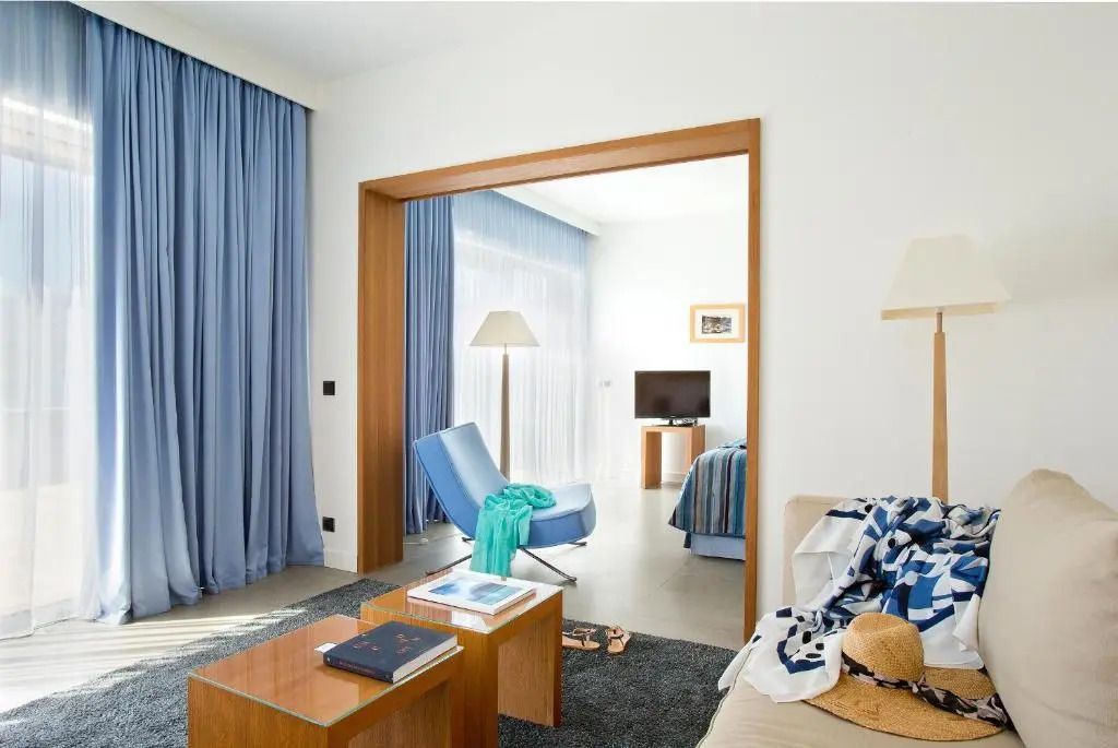 Helles Wohnzimmer einer Suite mit blauen Vorhängen und modernen Möbeln