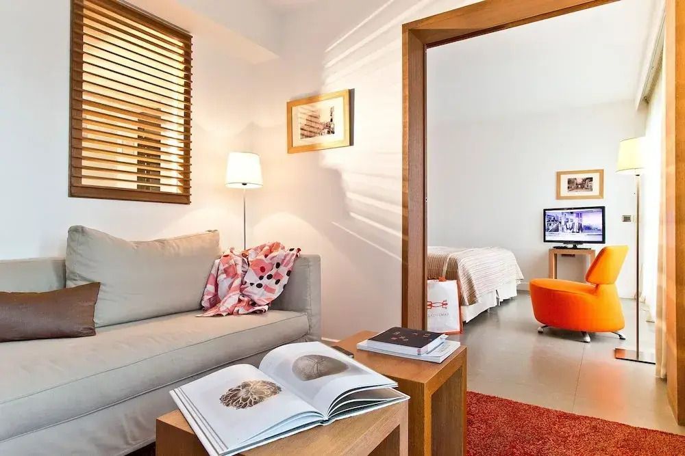 Helles Wohnzimmer mit Sofa und Holzdetails und Blick in ein Schlafzimmer