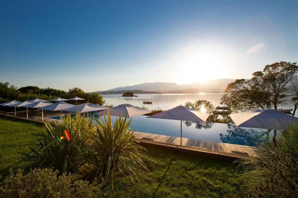 Infinity Pool mit Sonnenschirmen und Blick auf das Meer bei Sonnenuntergang