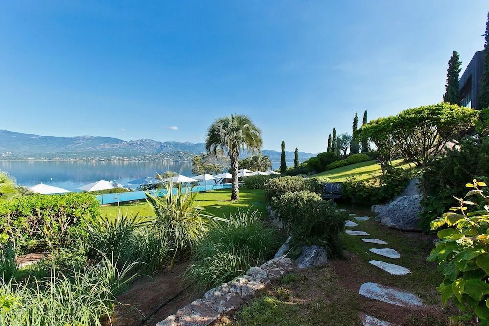 Gartenbereich mit Blick auf einen Infinity Pool und den See im Casadelmar Hotel
