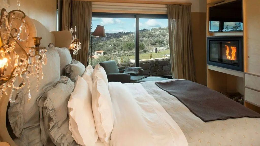 Elegantes Doppelzimmer mit großem Bett und Aussicht auf grüne Landschaft durch ein Fenster.
