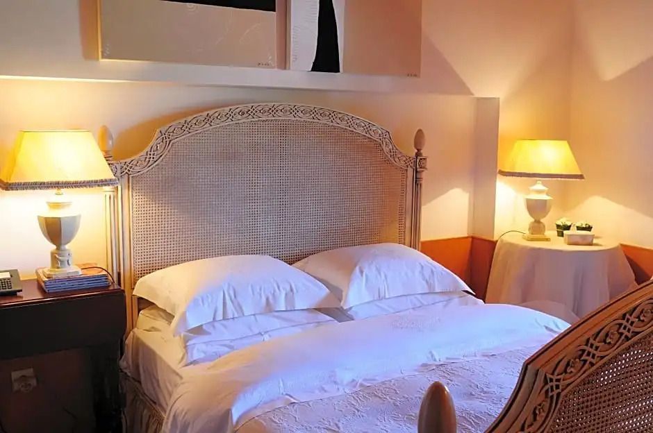 Schlafzimmer mit kunstvollem Kopfteil und stilvoller Beleuchtung neben einem Doppelbett