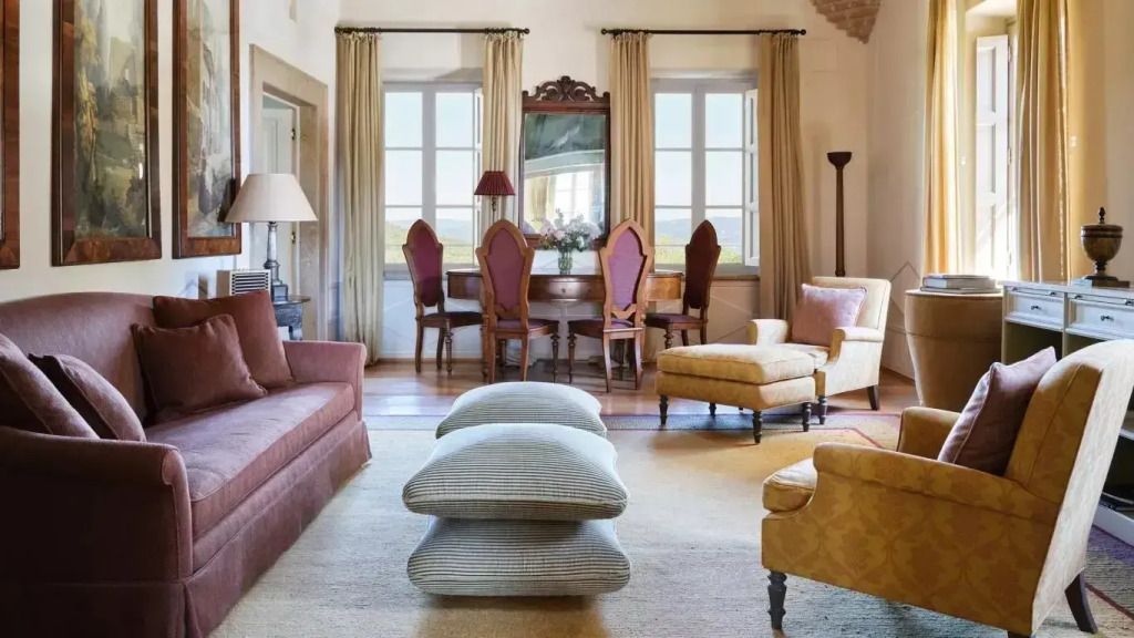 Stilvoller Salon mit Sofas und klassischem Esstisch vor großen Fenstern