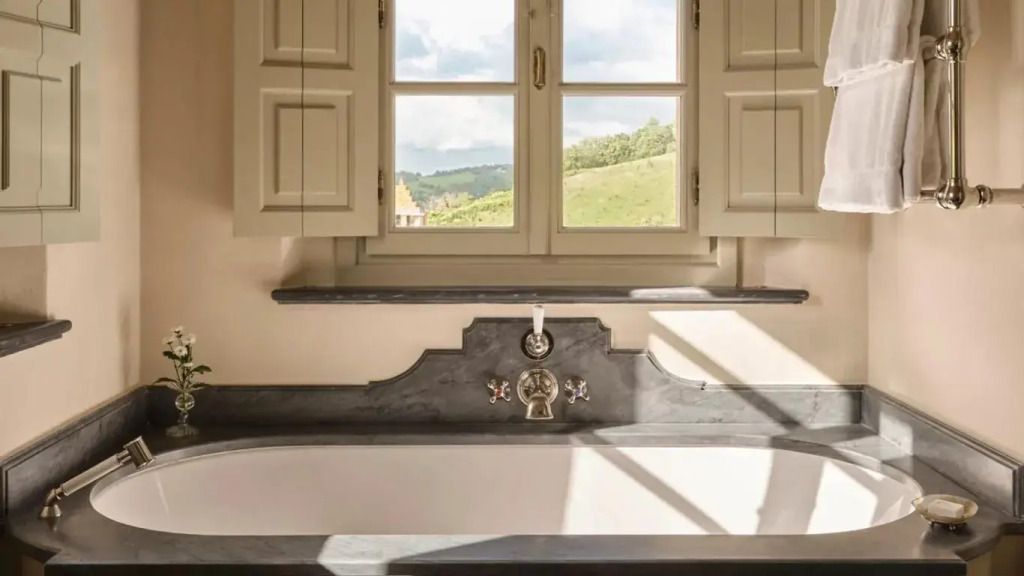 Badezimmer mit großer Wanne und Blick auf eine idyllische Landschaft