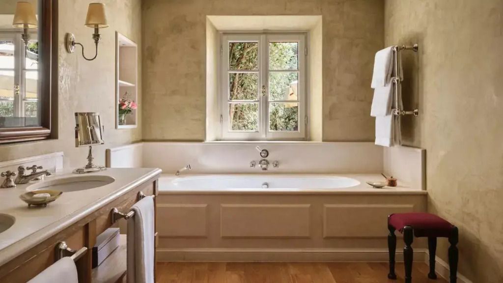 Badezimmer mit Badewanne und großem Fenster mit Blick ins Grüne.