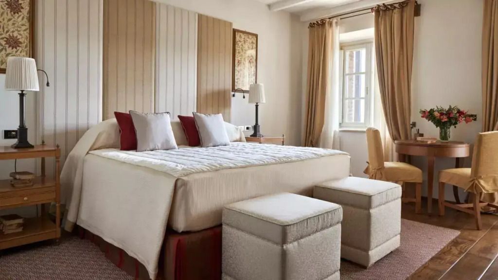 Hell eingerichtetes Schlafzimmer mit Doppelbett und Fenster mit Blick auf die Natur.