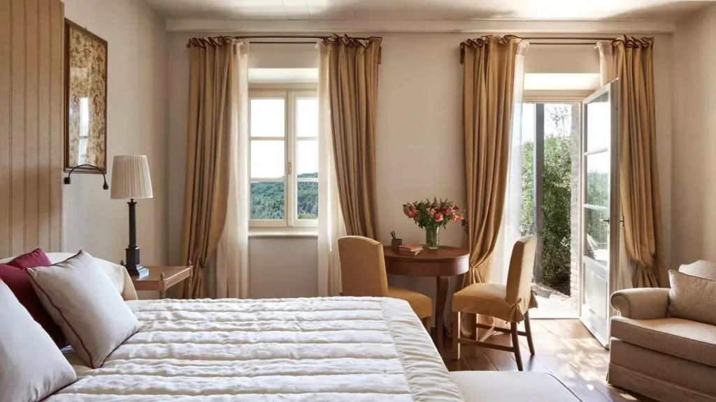 Schlafzimmer mit großem Bett und Sitzbereich mit Blick auf die Landschaft.