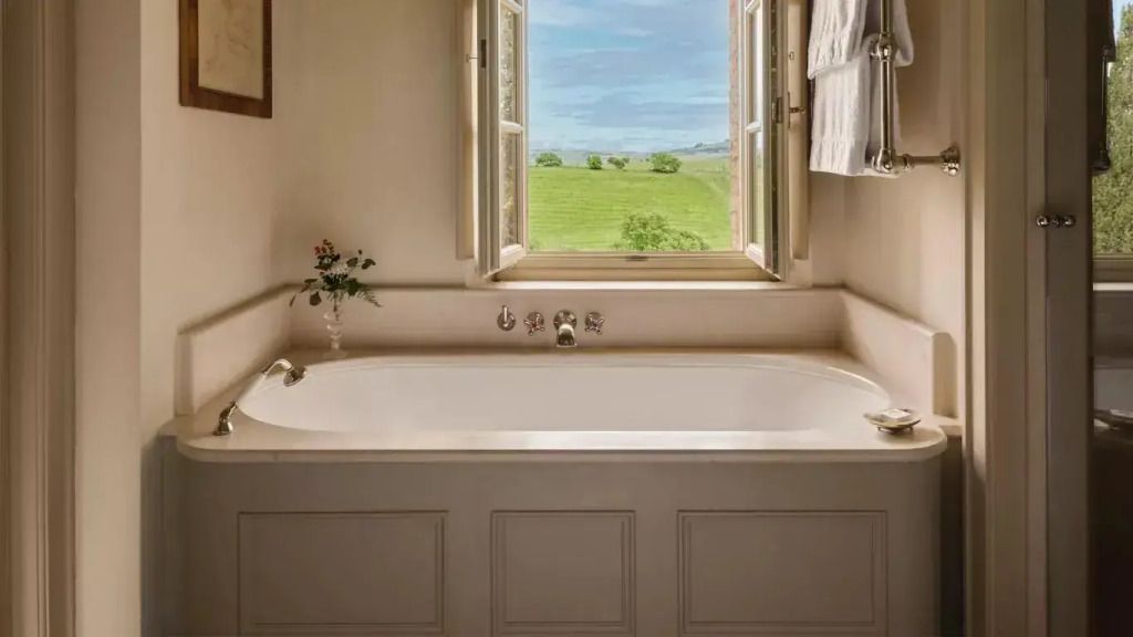 Badezimmer mit freistehender Badewanne und Blick auf die toskanische Landschaft