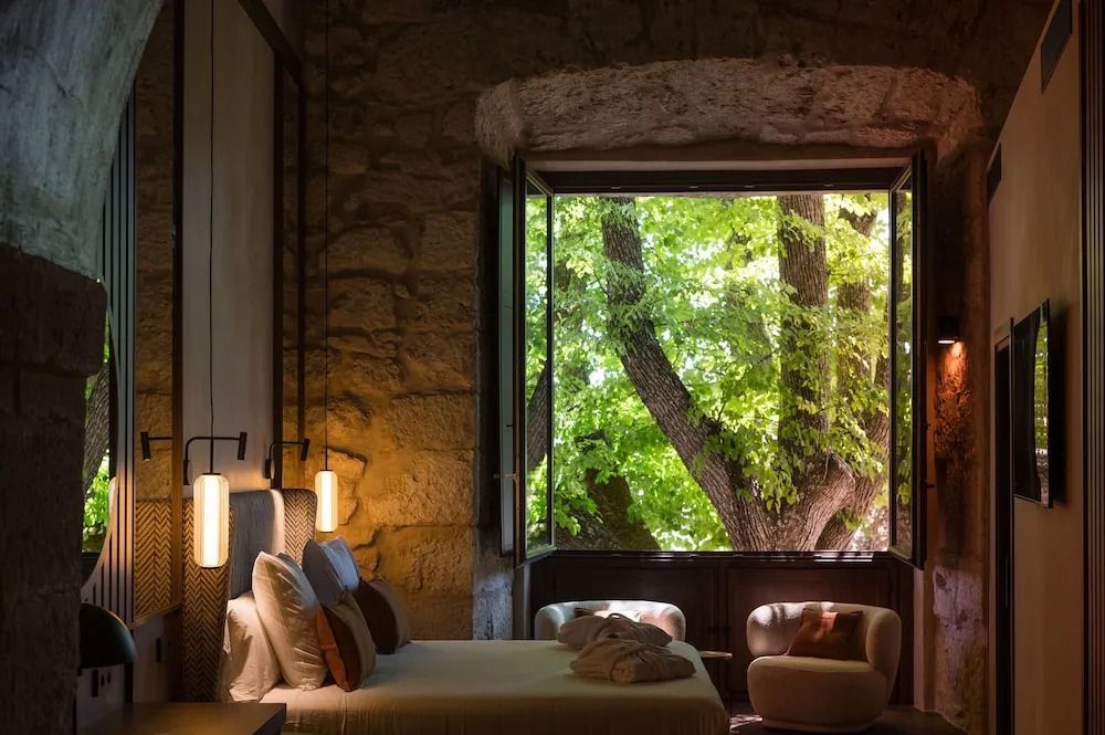 Schlafzimmer mit offenem Fenster, Blick auf Baum und gemütlicher Beleuchtung