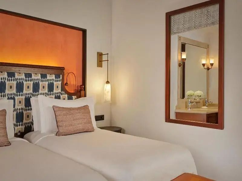 Gemütliches Bett mit dekorativem Kopfteil und elegante Beleuchtung im Deluxe-Zimmer.