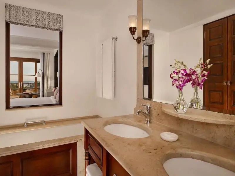Modernes Badezimmer mit Doppelwaschbecken Marmoroberflächen und Blumenakzenten.