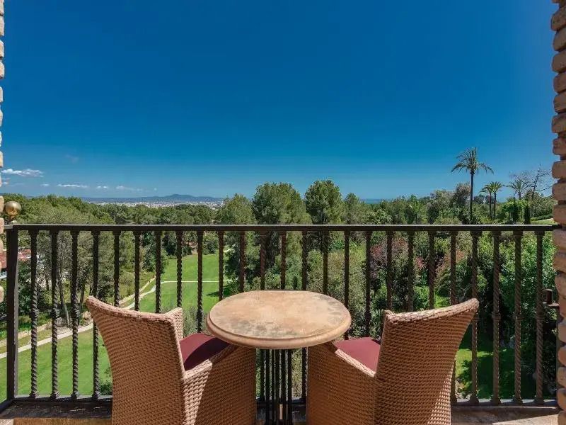 Balkon mit Sitzgelegenheit und spektakulärem Ausblick auf üppige Gärten und die Bucht.