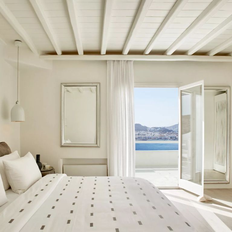 Stylisches Zimmer mit Meerblick durch offene Balkontür und Doppelbett