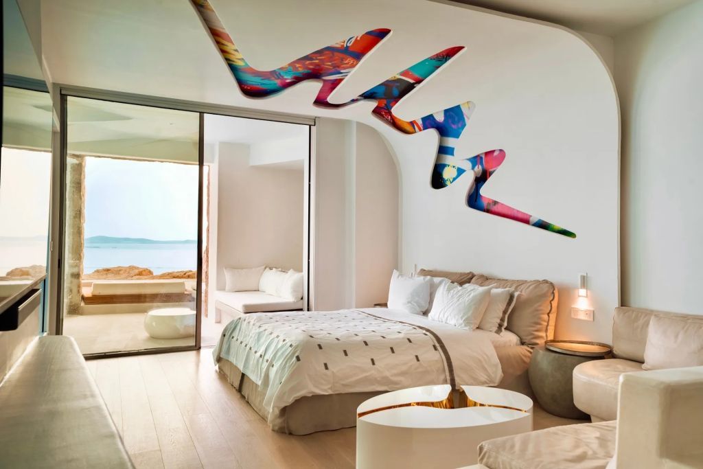 Luxuriöser Schlafbereich mit modernem Kunstwerk an der Wand und Balkonblick auf das Meer