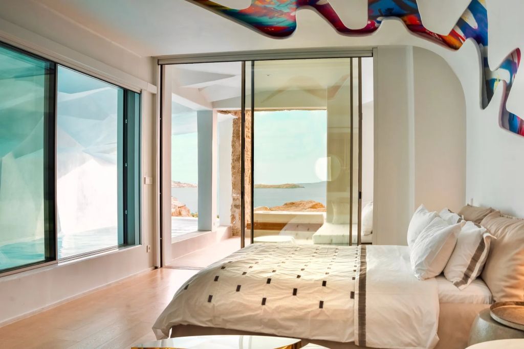 Geräumiges Schlafzimmer mit großen Fenstern und direktem Zugang zur Terrasse mit Meerblick