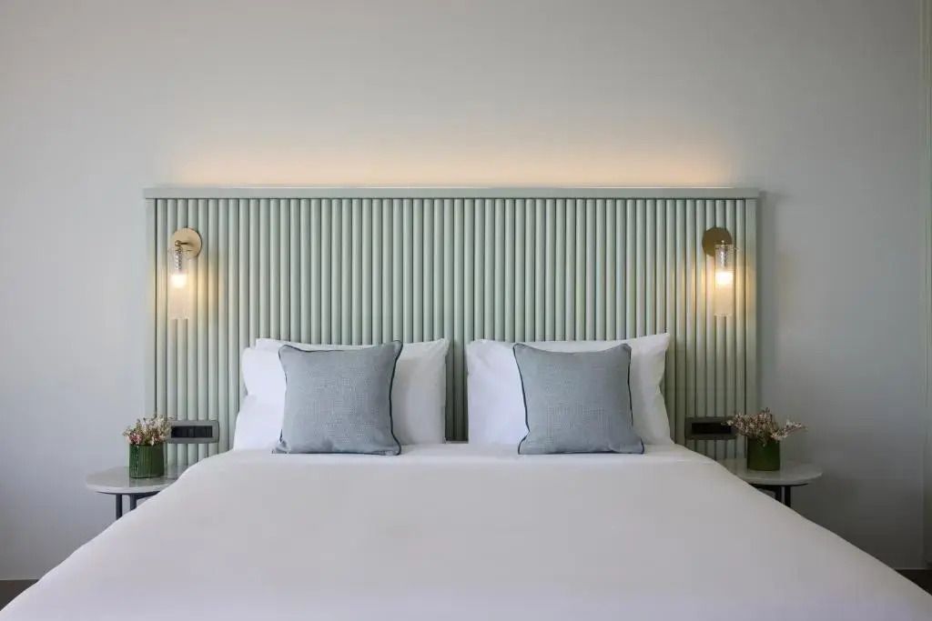 Elegantes Doppelbett mit blau verzierten Kissen und sanfter Beleuchtung.