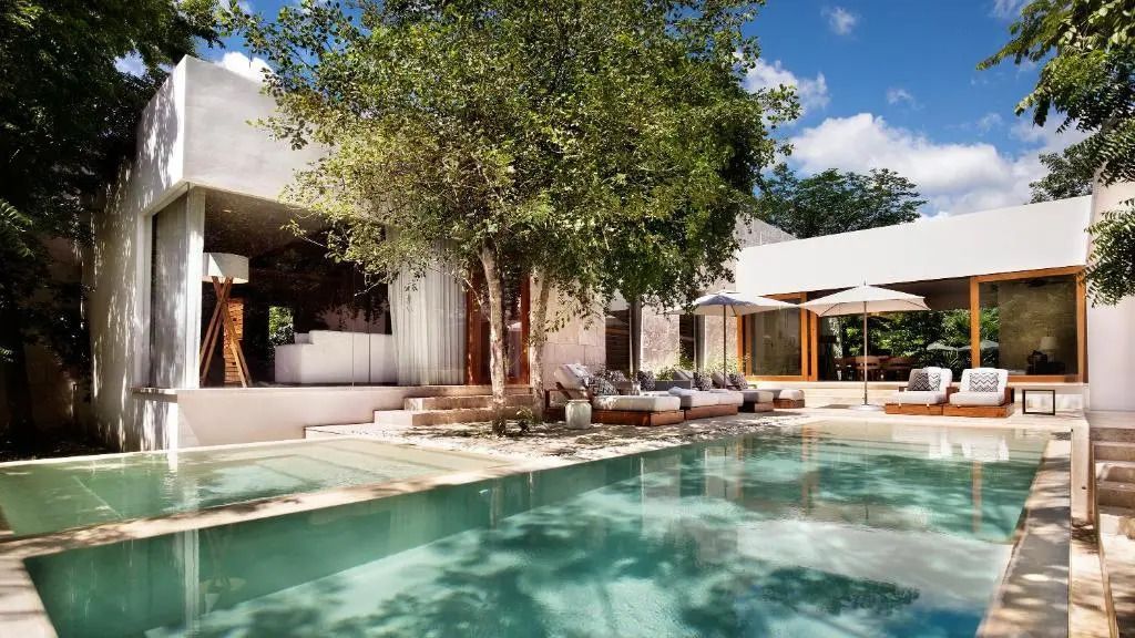 Poolbereich mit Sofa unter Baum, moderne Architektur im Hintergrund