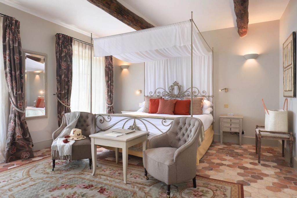 Luxuriöses Zimmer mit Himmelbett, eleganten Sesseln und einer einladenden Atmosphäre.