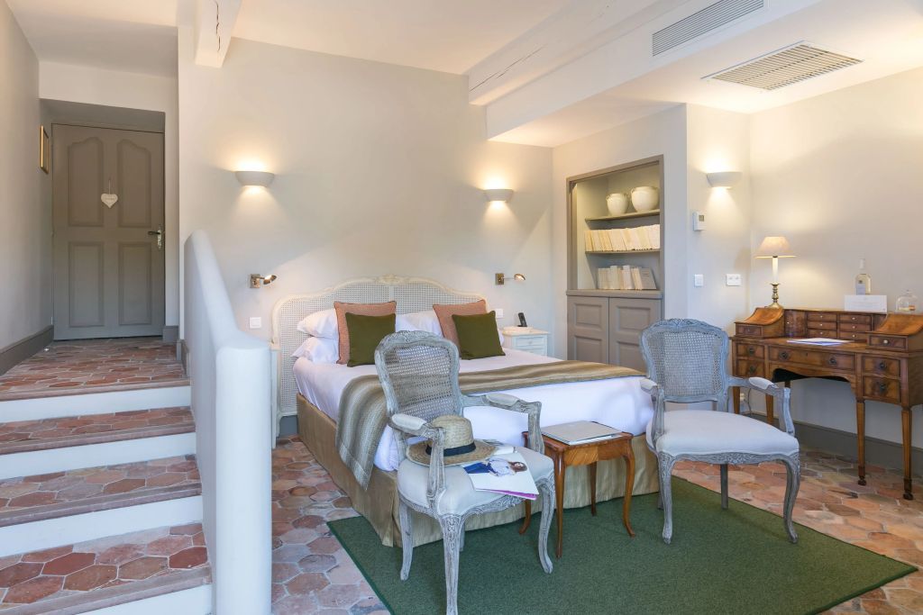 Einladendes Gästezimmer mit Doppelbett, stilvollen Sesseln und dezenter Beleuchtung.