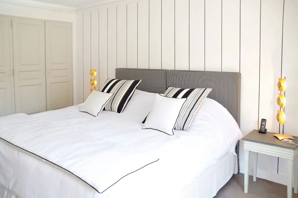 Modernes Schlafzimmer mit schlichter Wandvertäfelung und stilvoller Bettwäsche.