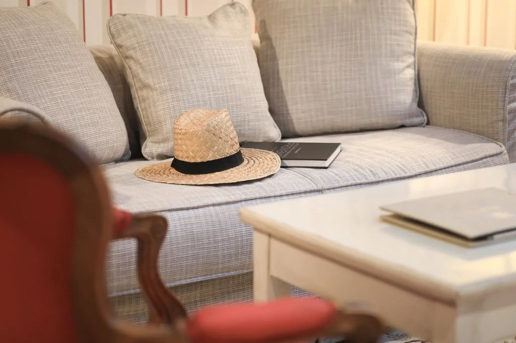 Gemütliches Sofa in der Suite mit Strohhut und Notizbuch