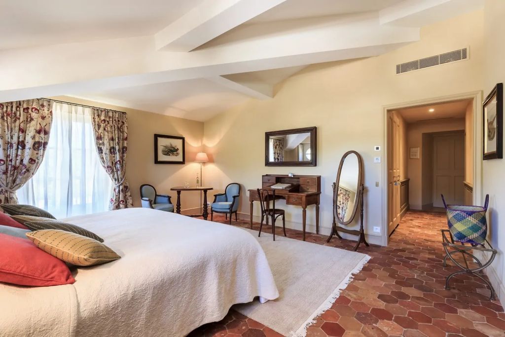 Elegantes Schlafzimmer mit Doppelbett, rustikalen Fliesen und Holzmöbeln