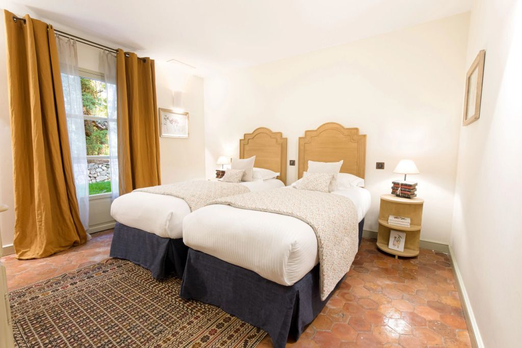 Zimmer mit zwei Einzelbetten und warmen Holzakzenten im Hotel Le Château de Berne.