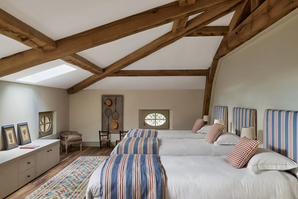 Geräumiges Zimmer mit Holzbalkendecke und drei Betten.