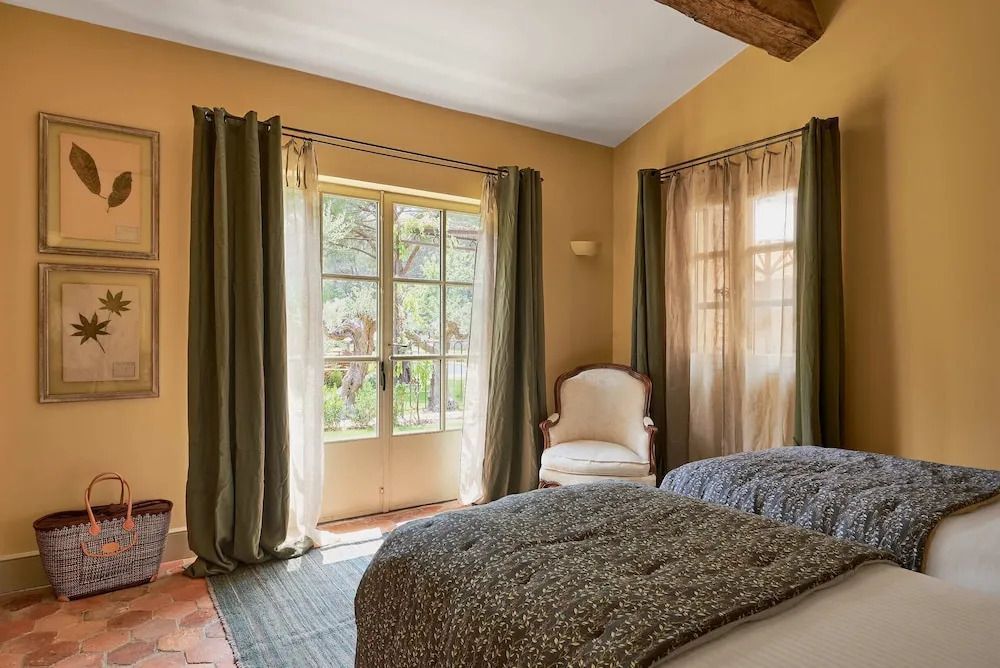 Schlafzimmer mit zwei Betten und klassischem Sessel neben großen Fenstern im Vanado Villa