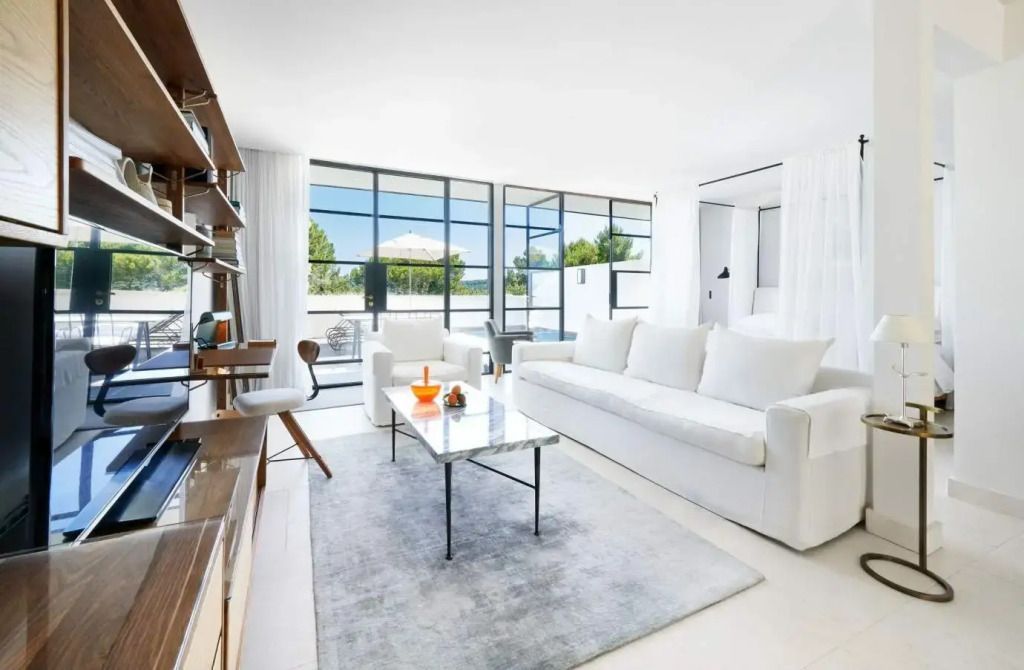 Geräumiges Wohnzimmer in hellen Farben mit großen Fenstern und Designer-Möbeln