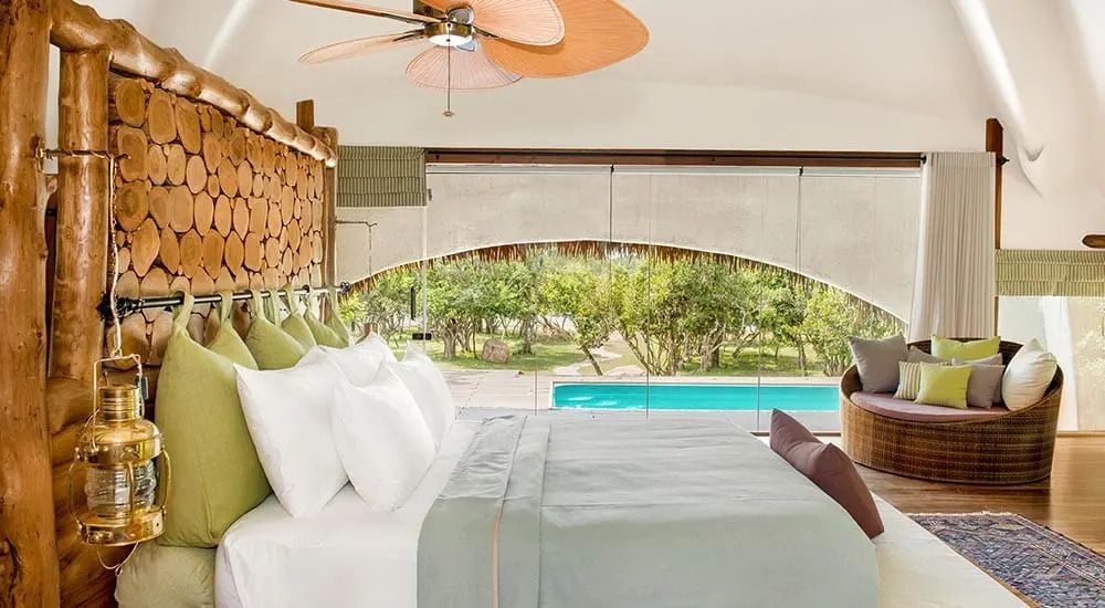 Elegantes Bett im Zimmer mit Poolblick und warmen Erdtönen
