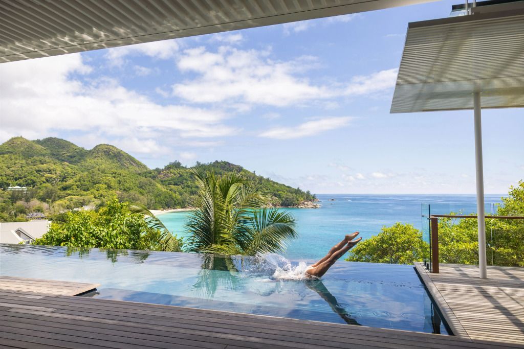 Infinity-Pool mit Blick auf das Meer und grüne Hügel im Hintergrund