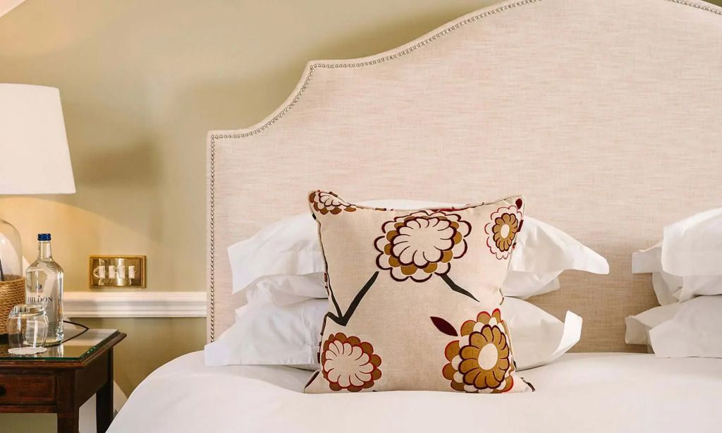 Zierkissen auf einem luxuriösen Bett mit detailreichem Kopfteil.