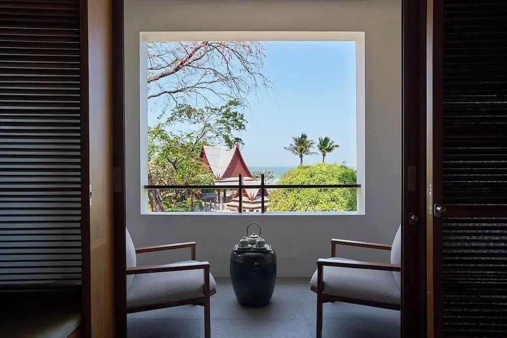 Zimmerausblick auf tropische Gärten und Meer im Hintergrund.