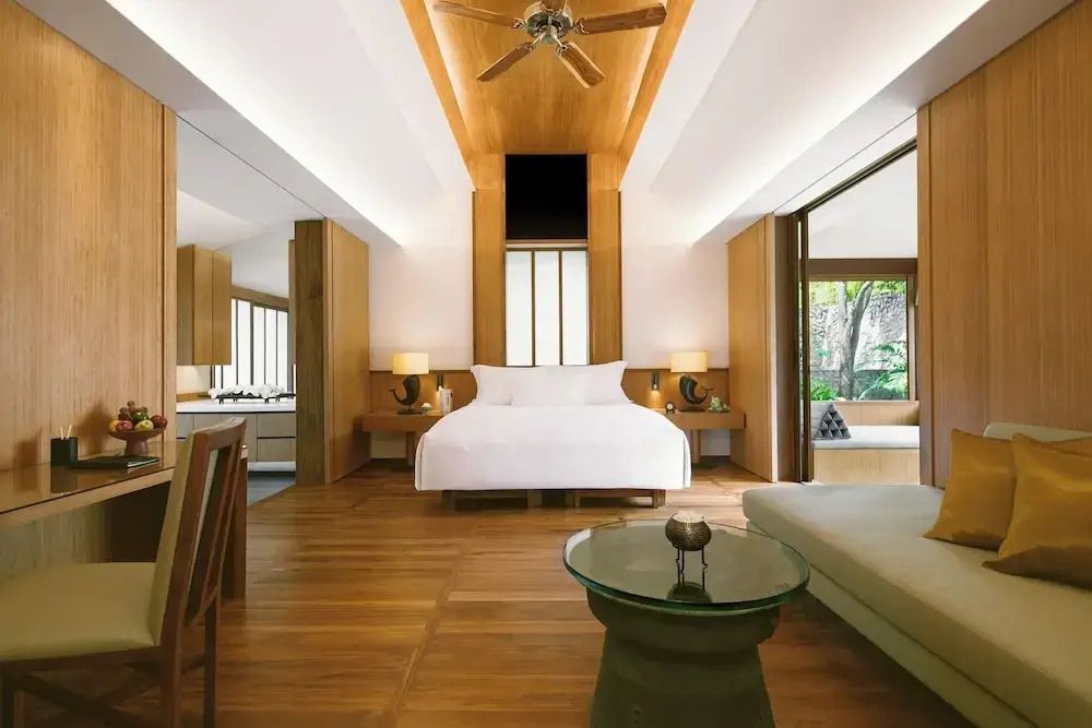 Hell eingerichtetes Hotelzimmer mit Holzboden und Blick ins Grüne