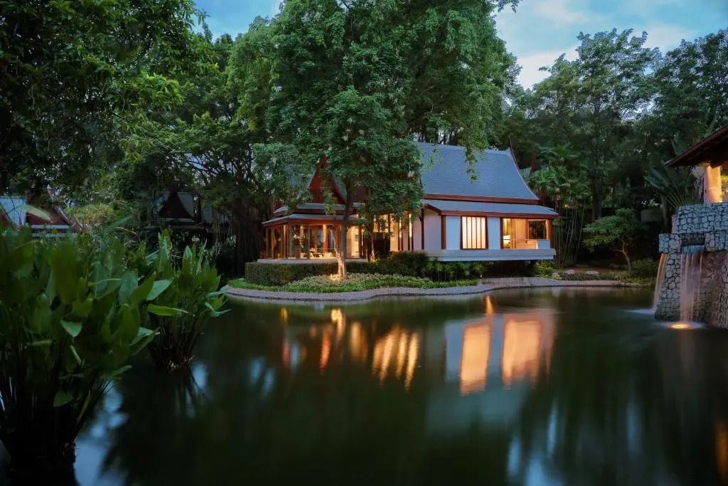 Beleuchtete Villa in traditionellem Stil an einem ruhigen Teich am Abend