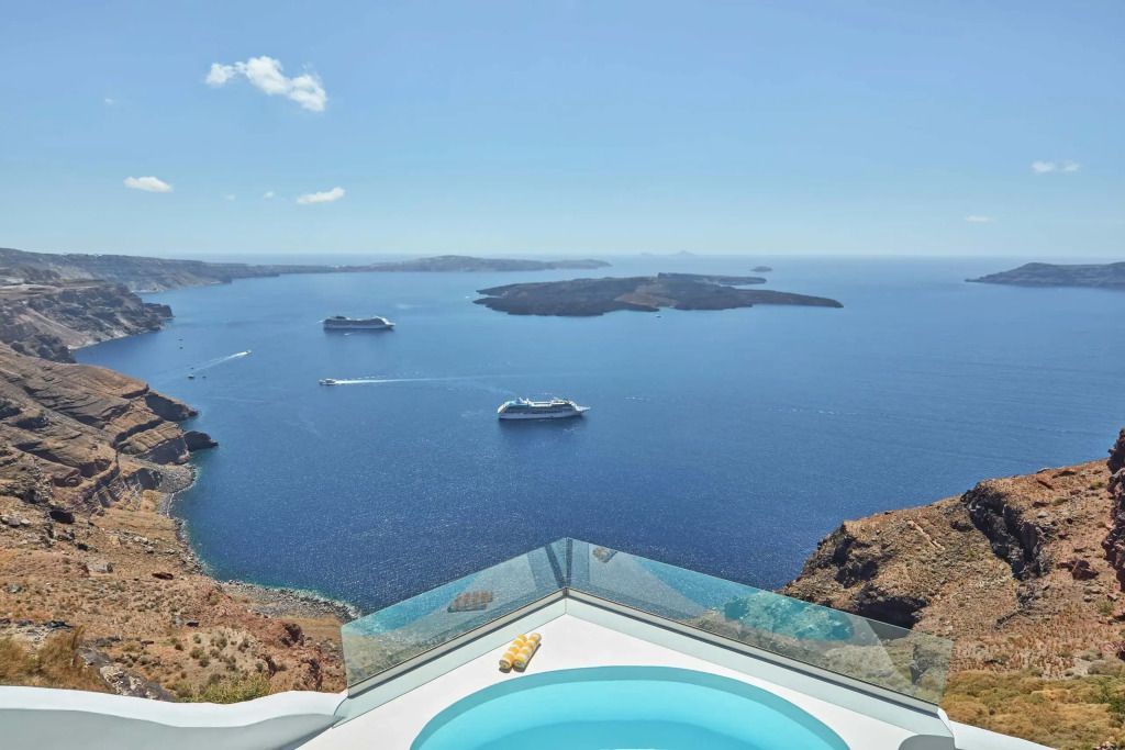 Panoramablick auf die Bucht von Santorini mit einem eleganten Infinity Pool im Vordergrund